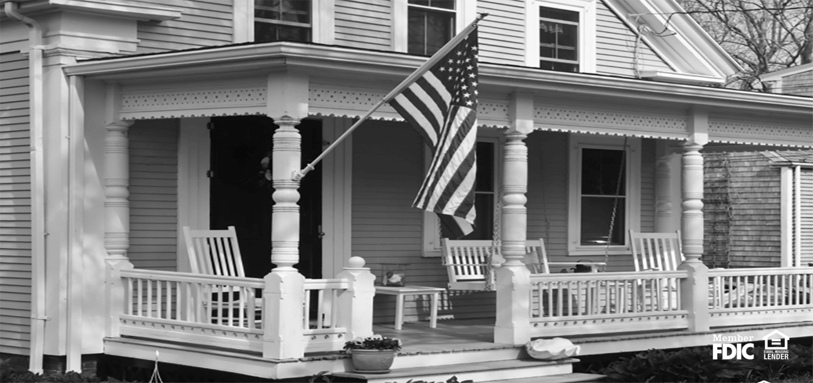 Beautiful Victorian style house with big front porch and an American flag flying 