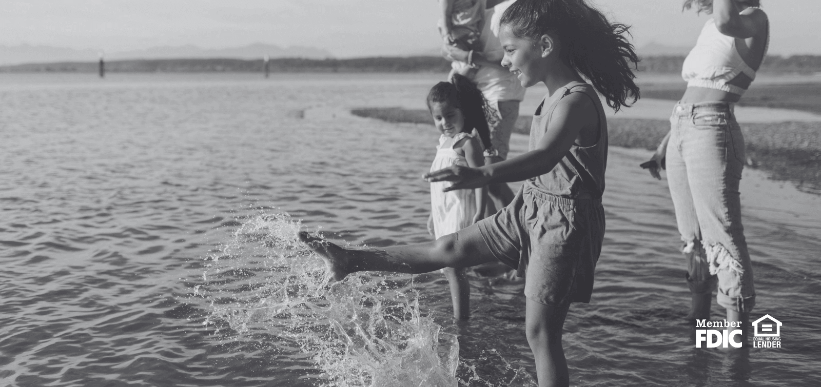 children and adults playing in the water at a beach