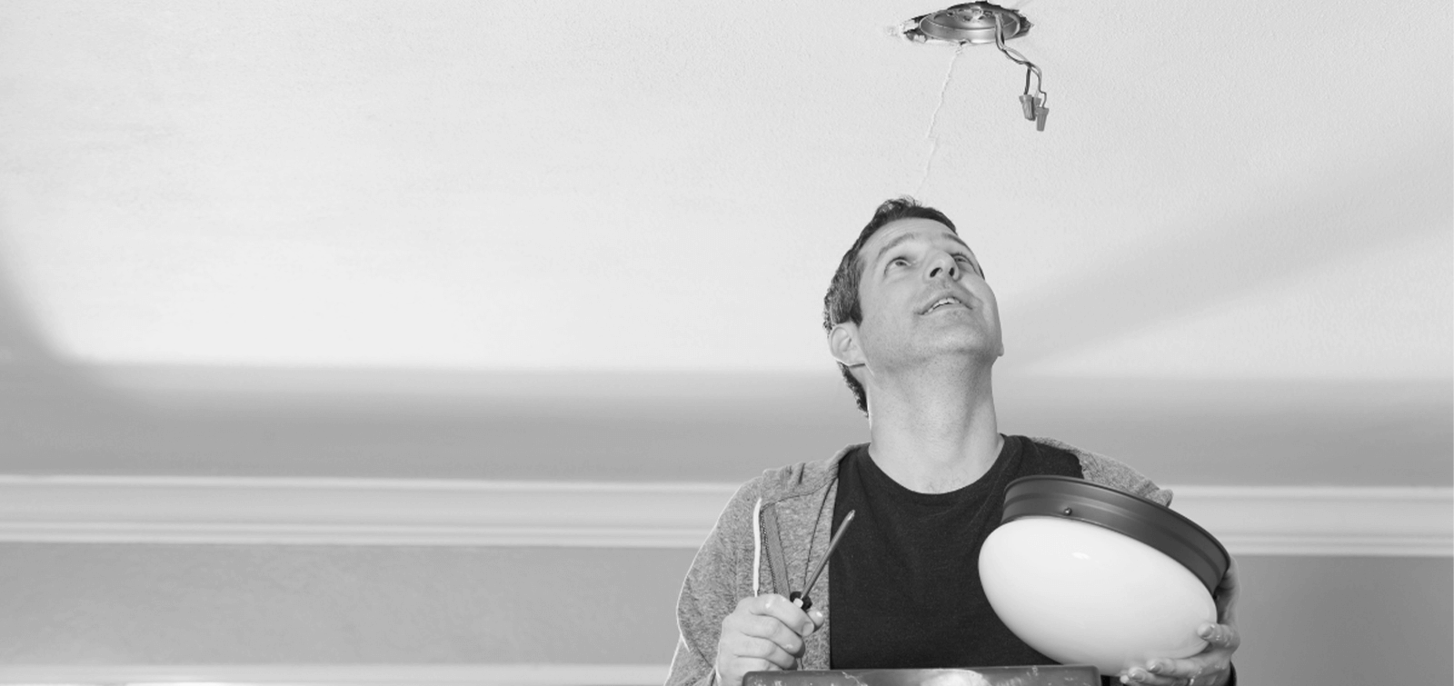 a man repairs a light fixture during spring home improvements