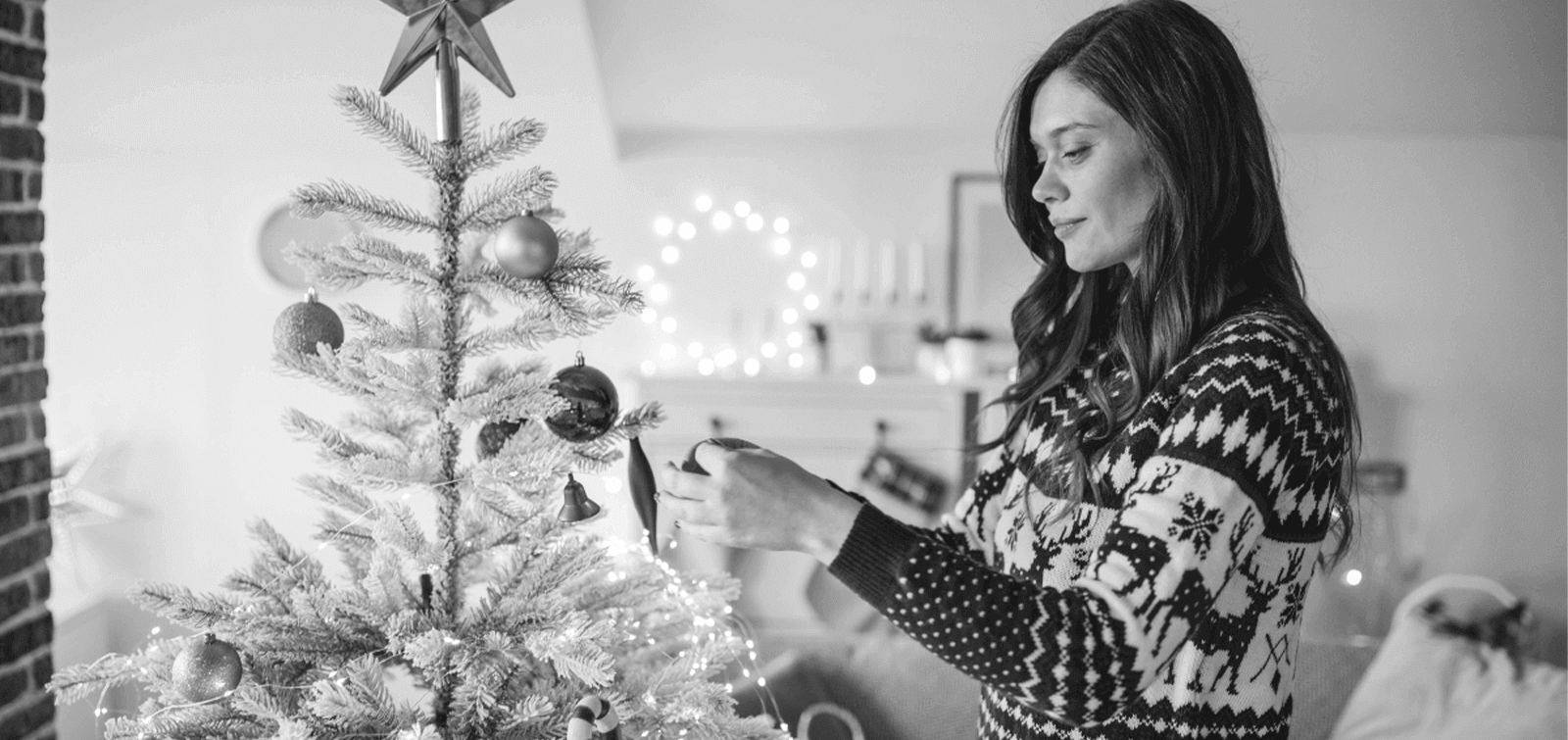 a woman decorates her holiday tree