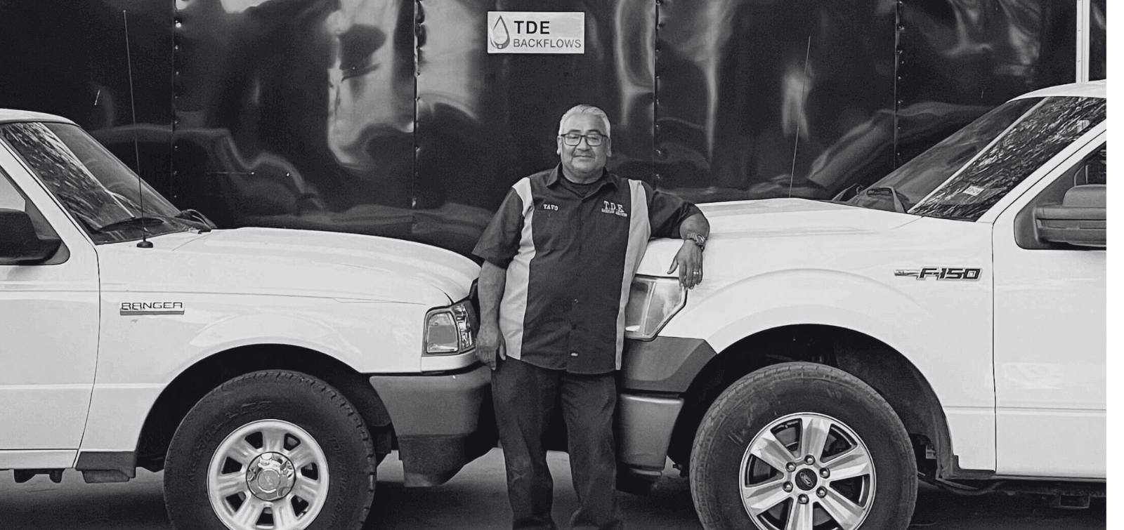 TDE owner poses with two of his work trucks