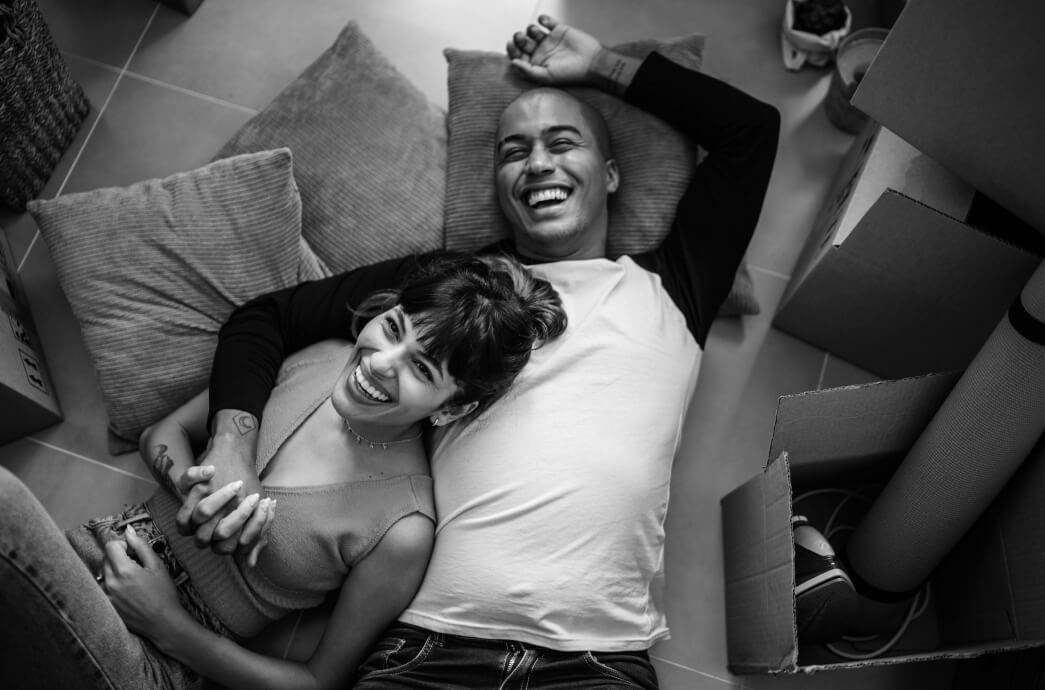 Couple laying on a floor of pillows smiling together in new home they moved into