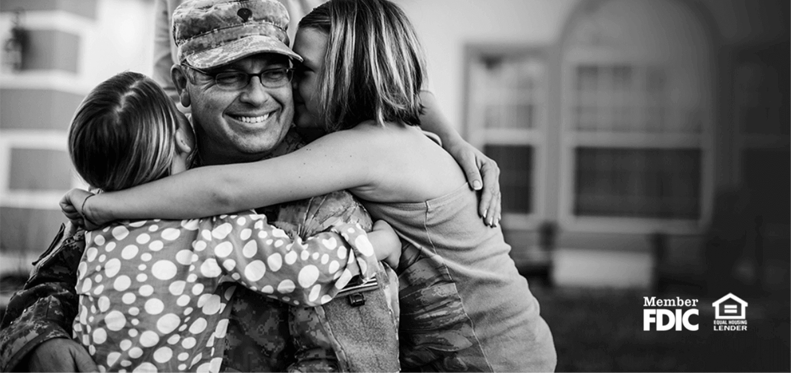 a military father hugs his two daughters