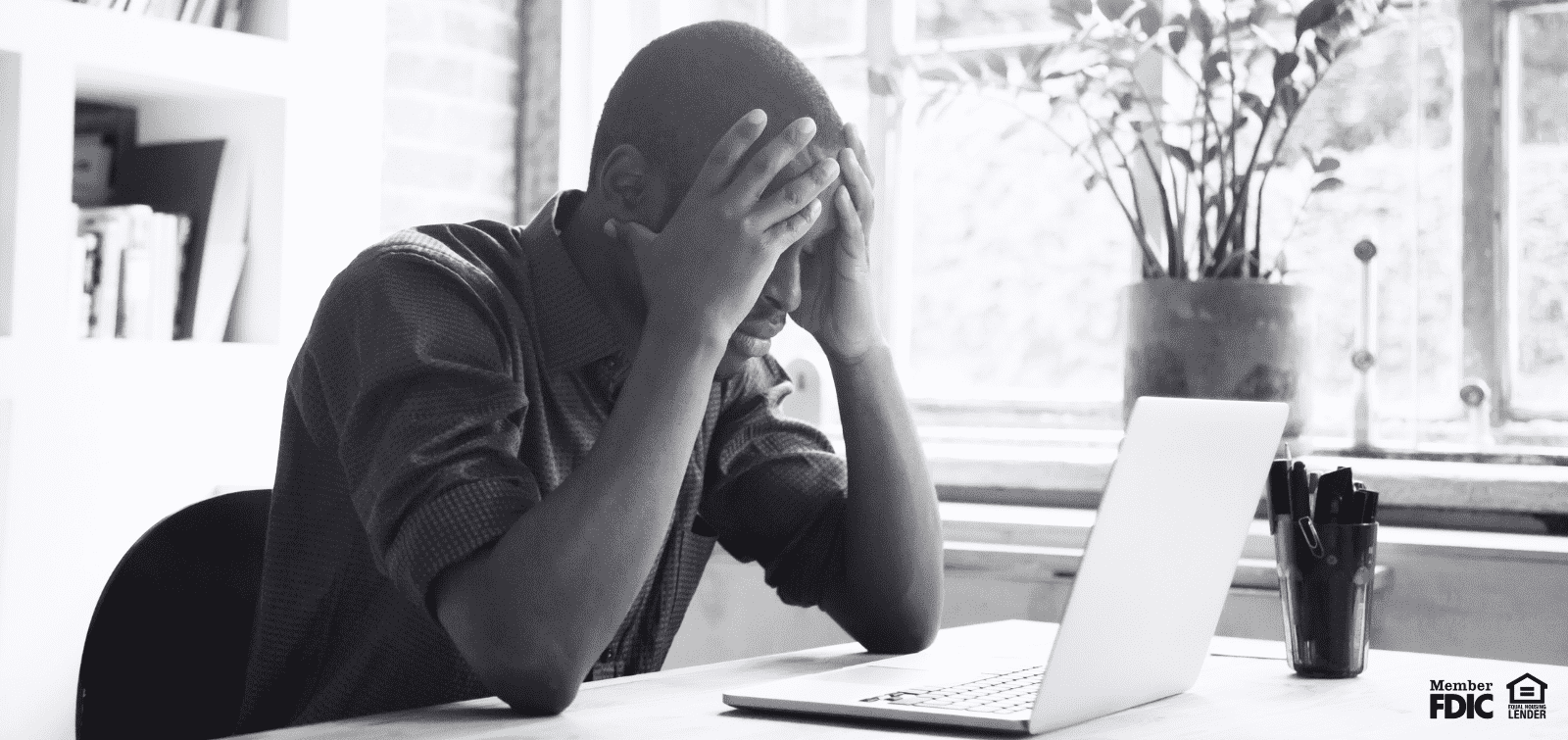 A man holding his head in his hands upset because he fell prey to email scamming.