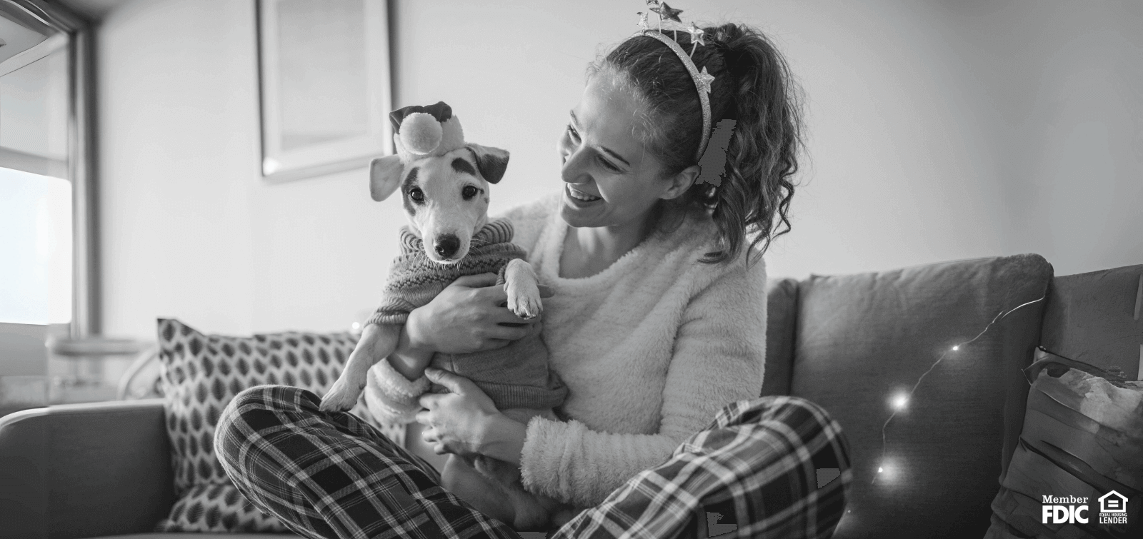 A young woman hugs her dog wearing holiday clothes and pajamas
